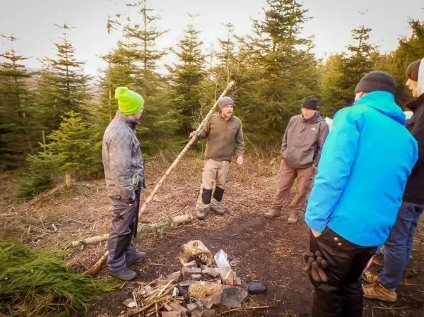 Gruppe diskutiert um ein kleines Bodenfeuer in einem Waldgebiet