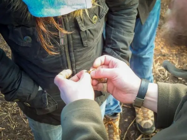 Hände binden eine Schnur um einen Reißverschluss an einer Jacke