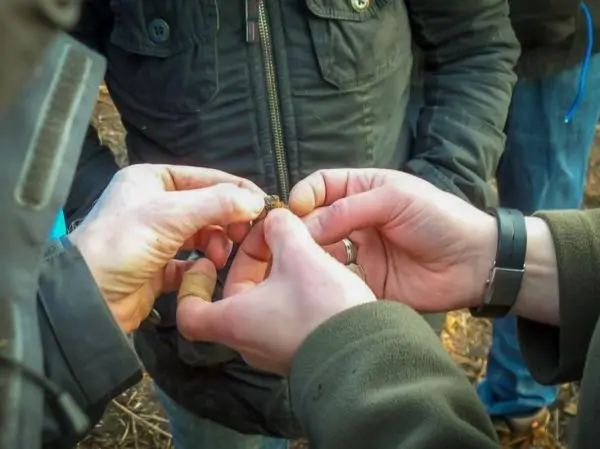 Hände halten einen kleinen Gegenstand, während mehrere Personen um sie versammelt sind