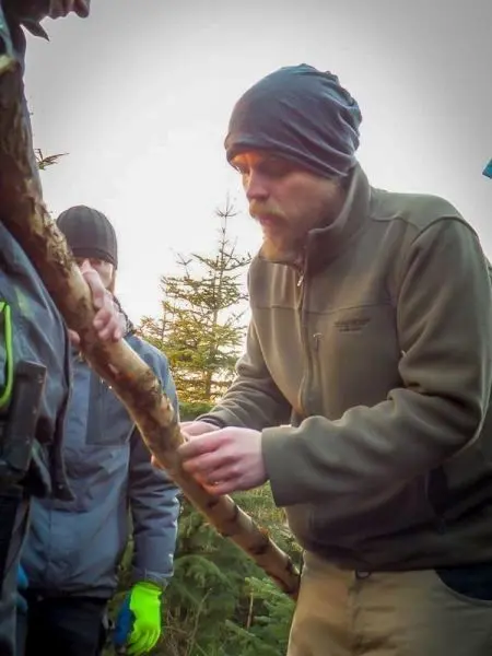 Holzstück wird bearbeitet, während eine Person Unterstützung bietet