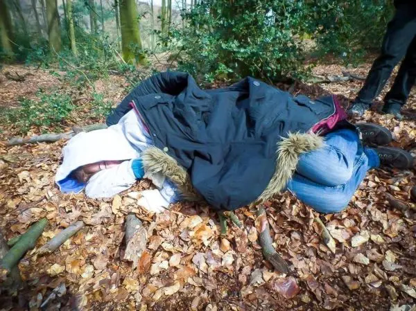 Improvisierte Trage aus Decken und Laub auf dem Boden im Wald