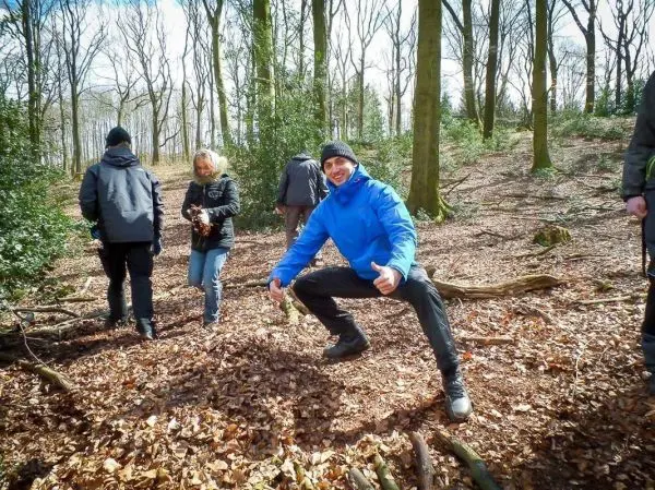Person posiert lächelnd im Wald zwischen anderen Personen