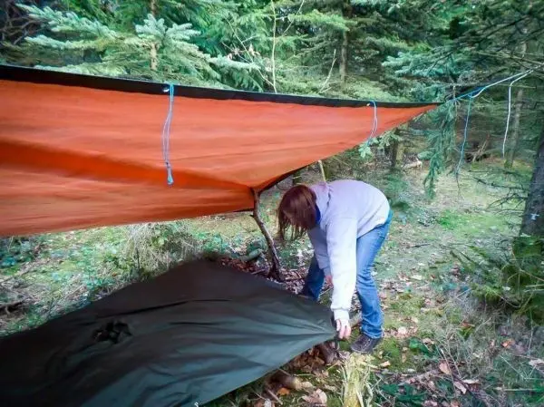 Tarp-Notunterkunft wird aufgestellt und mit Unterlage gesichert