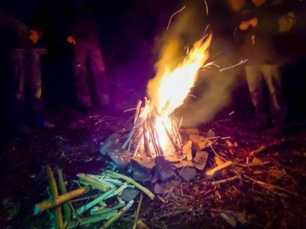 Feuer brennt in einem Steinkreis, Personen stehen daneben