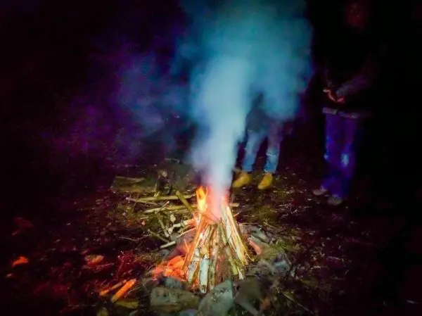 Feuer brennt mit Rauch und Holzscheiten im Hintergrund