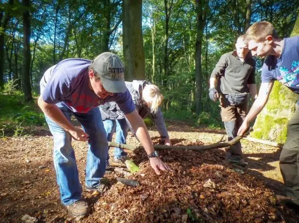 Gruppenteilnehmer sammeln Laub und Äste auf dem Waldboden