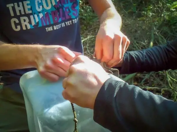 Hände binden eine Schnur um einen Behälter in der Natur