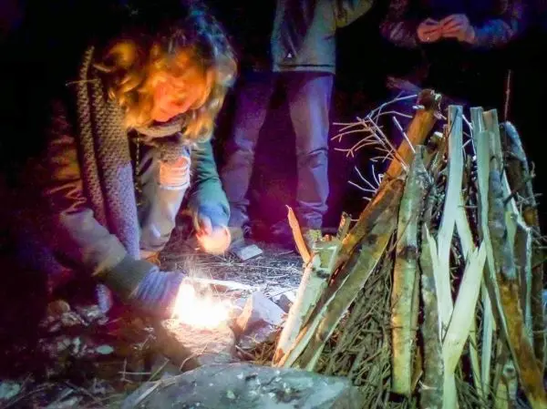 Kleine Flamme entzündet Zunder vor einem Holzstapel