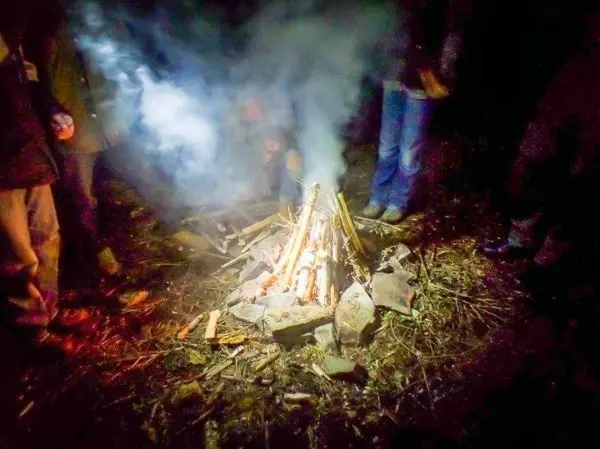 Kleine Flamme mit Rauch und Holzscheiten auf dem Boden