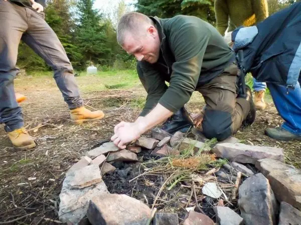 Mann bereitet Feuerstelle mit Steinen und Zunder vor