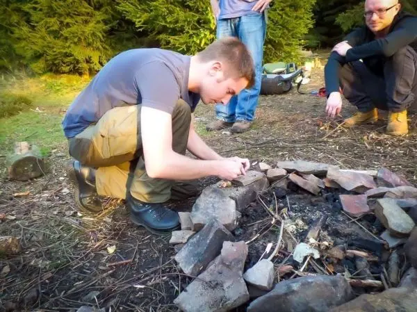 Mann bereitet Zunder im Feuerkreis aus Steinen vor