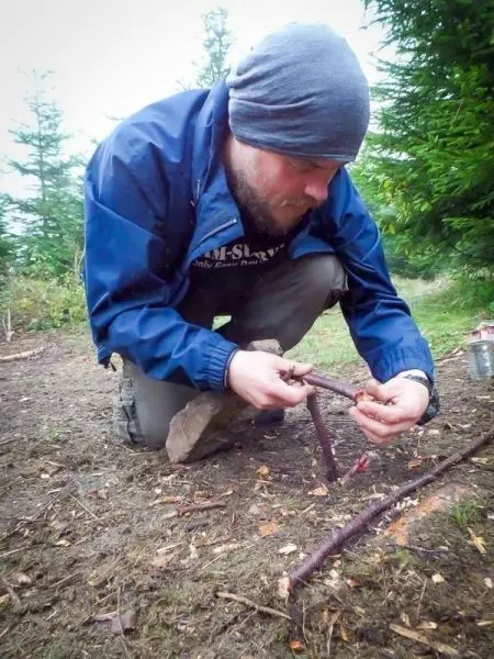 Mann kniet auf dem Boden und bearbeitet Holzstücke für eine Konstruktion