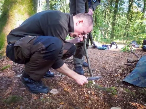 Messer schneidet in einen Stock während einer Holzarbeit im Wald