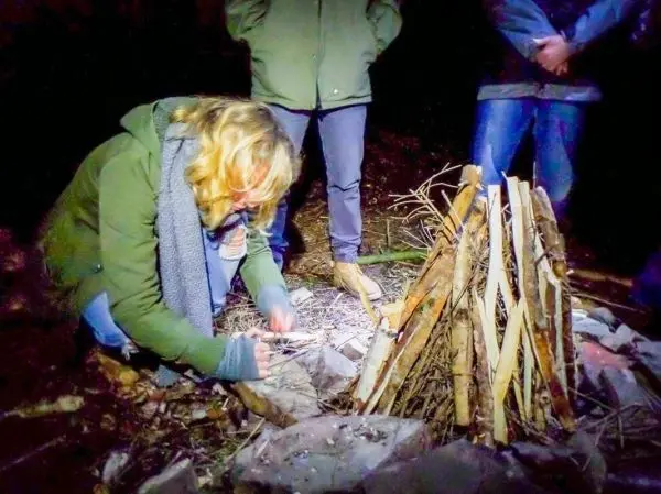 Person bereitet Feuerstelle mit Holz und Zunder vor