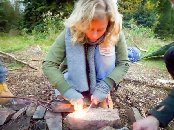 Person entzündet Feuer mit einem Feuerstein im Wald beim Survival Training