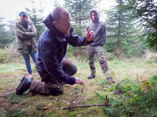 Person erklärt eine Falle im Wald beim Survival Training