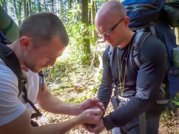 Person hilft anderer Person beim Anlegen einer Bandage im Wald