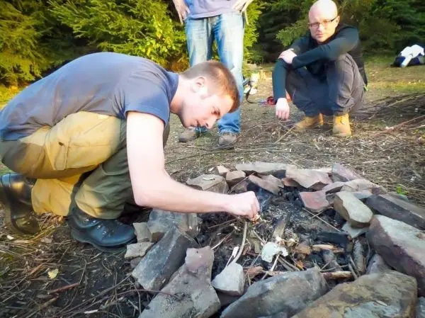 Person zündet Feuerstelle mit kleinen Ästen an beim Survival Training