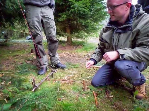 Schlagfalle (Figure-Four) auf dem Boden mit zwei Holzstücken und Schnur aufgebaut