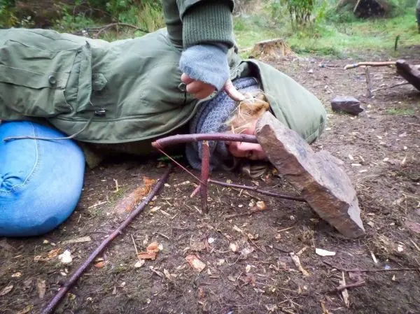 Schlagfalle (Figure-Four) mit Stein und Ästen auf dem Boden
