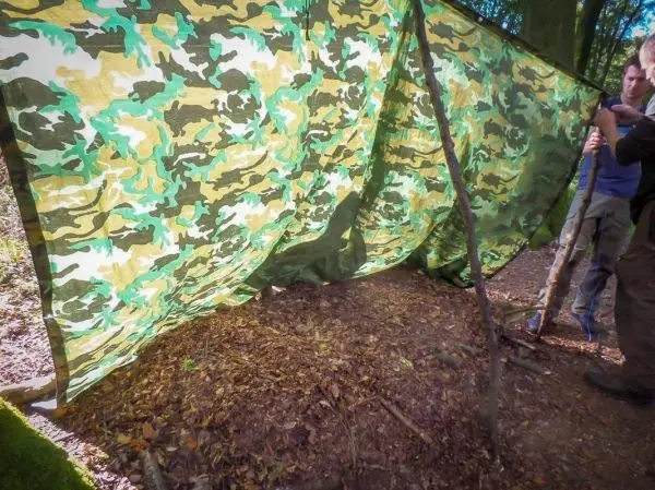 Tarp-Notunterkunft wird mit einem Stock und Abspannschnur aufgebaut