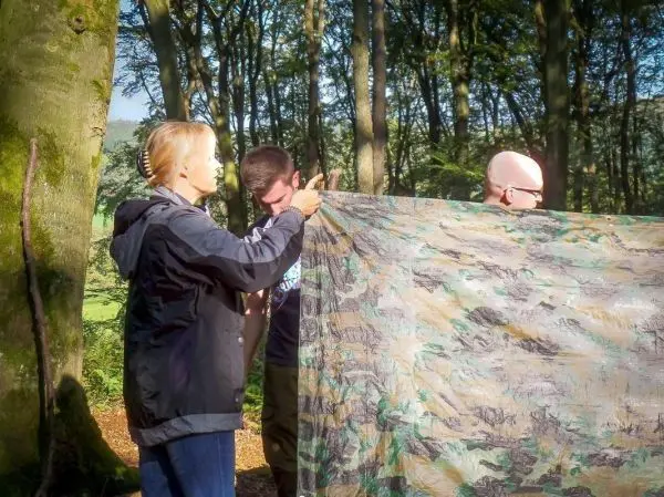 Tarp-Notunterkunft wird von zwei Personen gehalten und ausgerichtet