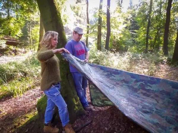 Tarp-Notunterkunft wird zwischen zwei Bäumen gespannt