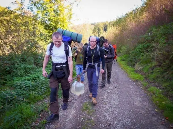 Wanderer tragen Rucksäcke und transportieren Wasserkanister auf einem Waldweg