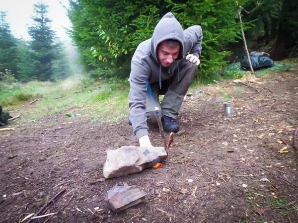 Zunder glimmt unter einem Stein, während ein Feuerstahl Funken erzeugt