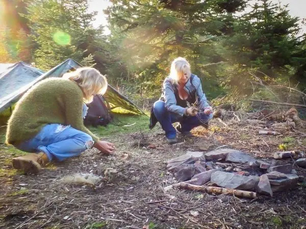 Zunder wird vorbereitet, während ein kleines Feuer aus Steinen brennt