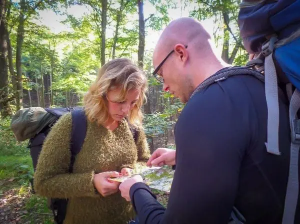 Zwei Personen betrachten eine Karte im Wald, um sich zu orientieren