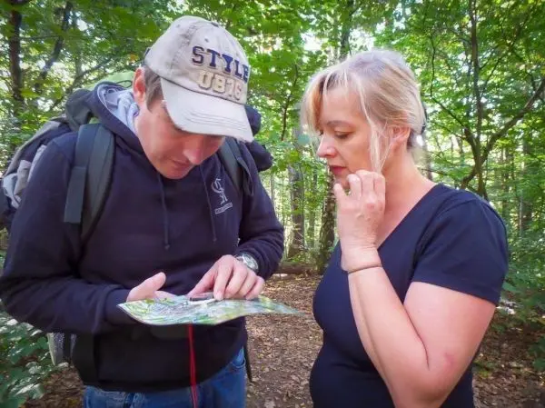 Zwei Personen betrachten gemeinsam eine Karte im Wald