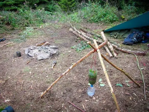 Dreibein mit Kessel hängt über einem kleinen Feuerplatz aus Steinen