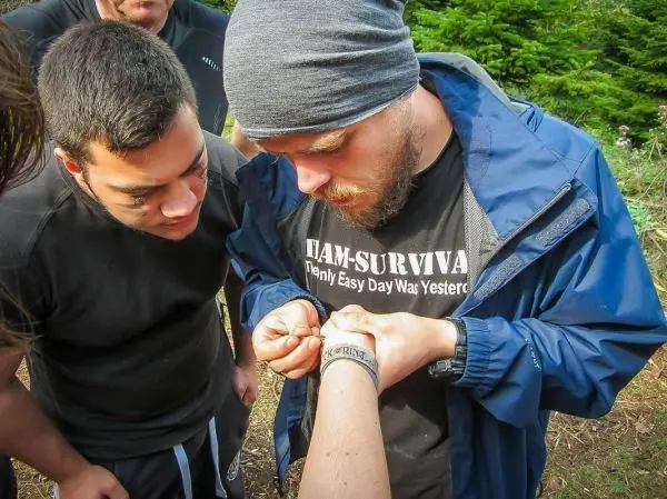 Ein Teilnehmer überprüft eine Bandage am Arm eines anderen