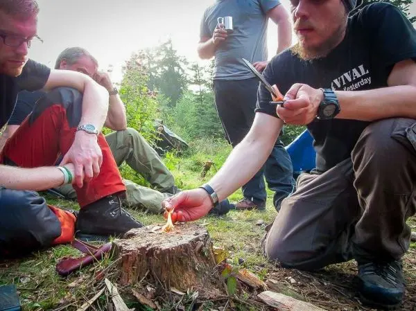 Feuerstahl erzeugt Funken auf Zunder in der Nähe von Teilnehmern