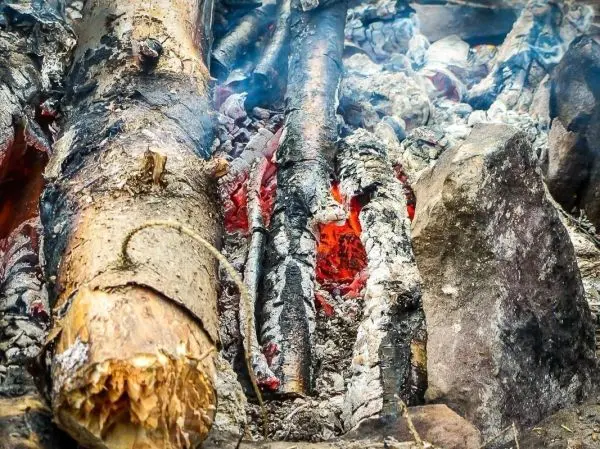 Glutnest glimmt zwischen verbrannten Holzstücken und Steinen