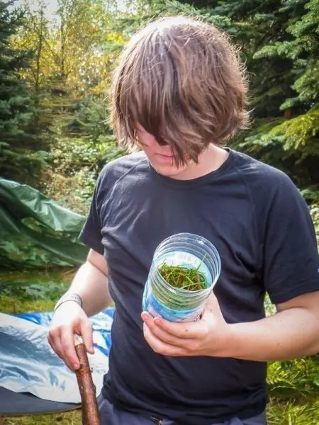 Junge hält ein Behältnis mit Zunder und einen Stock in der Hand