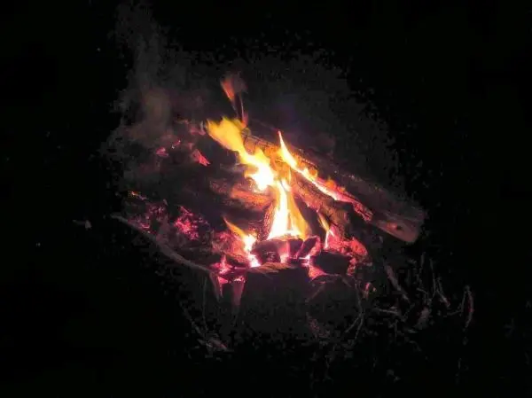 Kleine Flamme brennt auf einem Holzstapel in der Dunkelheit