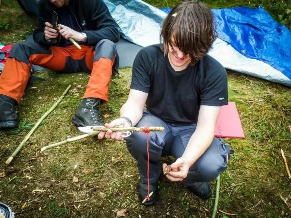 Messer bearbeitet Holzstück für eine selbstgebaute Konstruktion im Freien