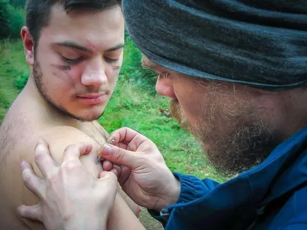 Person behandelt Wunde am Oberarm einer anderen Person beim Überlebenstraining