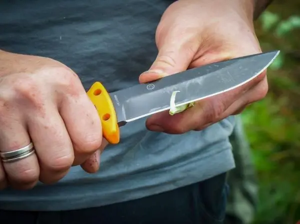 Person hält ein Messer mit orangefarbenem Griff in der Hand