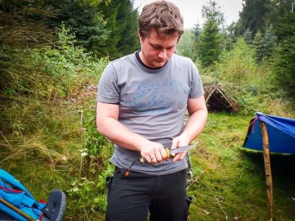 Person schneidet mit einem Messer in der Natur