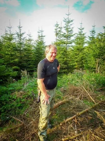 Person steht in einem Wald zwischen Bäumen und Gestrüpp
