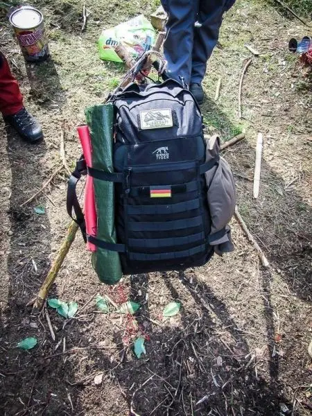 Rucksack mit zwei Matten und Stöcken auf dem Boden platziert