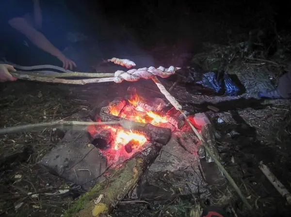 Stock mit Fleischstücken über Feuer gehalten