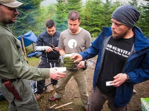 Vier Personen stehen im Wald und bereiten gemeinsam eine Mahlzeit vor