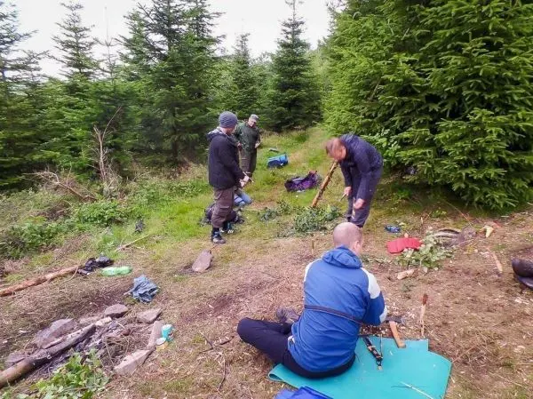 Gruppierung arbeitet im Wald an Holzstücken und Ausrüstung auf dem Boden