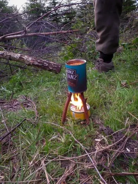 Hobo-Kocher mit Flamme auf improvisierter Stütze aus Holzstücken