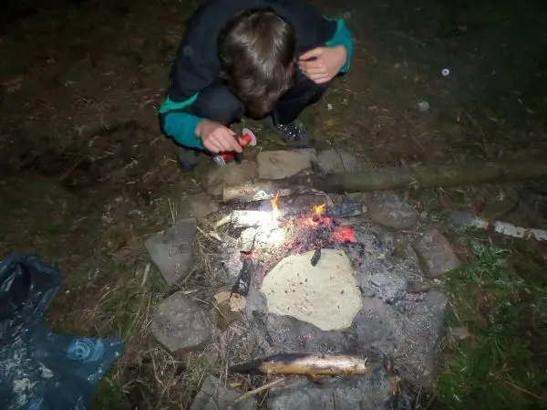 Kleines Bodenfeuer mit glühenden Kohlen und flachem Brot in der Nähe