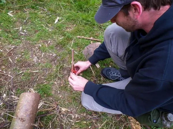 Mann bearbeitet Zunder mit einem Messer auf dem Boden